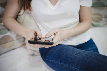 Young woman using mobile phone at home - EBBF03539