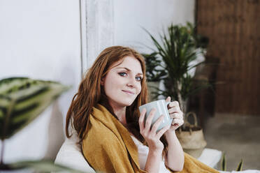 Lächelnde schöne Frau hält Kaffeetasse zu Hause - EBBF03583
