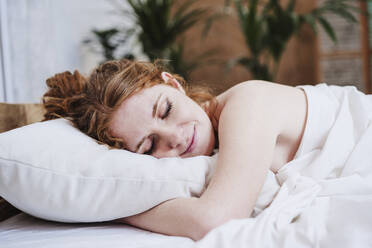 Hemdlose Frau mit Decke auf dem Bett liegend zu Hause - EBBF03628