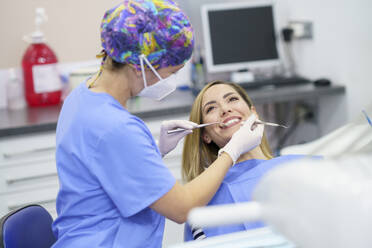 Female dentist examining patient's teeth at clinic during pandemic - JSMF02200