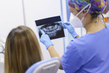 Eine Zahnärztin erklärt einem Patienten in einer Klinik eine medizinische Röntgenaufnahme - JSMF02208