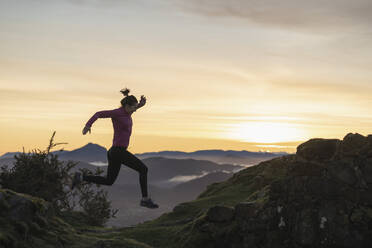 Junge Frau springt beim Laufen während des Sonnenaufgangs - SNF01423