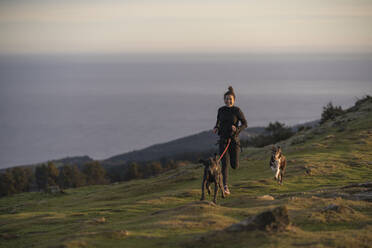 Female runner running with dogs in canicross style on hill - SNF01439