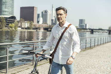 Businessman walking with bicycle in city - UUF23162