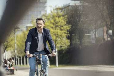 Mature male entrepreneur cycling bicycle on sunny day - UUF23200