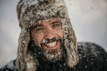 Cheerful man wearing hunters cap during winter - MJRF00488