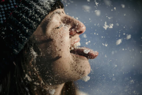 Playful woman sticking out tongue while snowing - MJRF00489