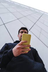 Man using smart phone by wall - ASGF00286