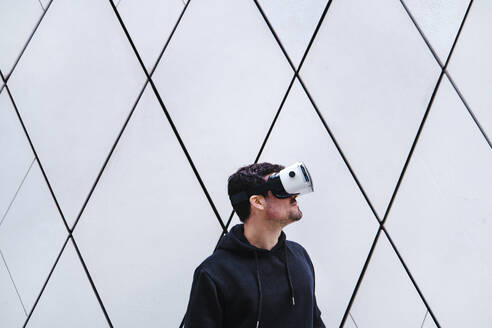 Junger Mann, der wegschaut und ein Virtual-Reality-Headset trägt - ASGF00287