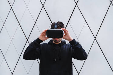 Mann hält Virtual-Reality-Headset an der Wand - ASGF00288