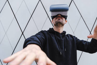 Young man gesturing while wearing Virtual reality headset outdoors - ASGF00289