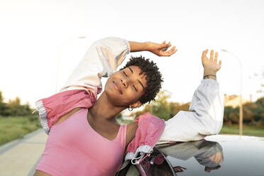 Woman with arms raised enjoying wind while travelling by car - JCCMF02544