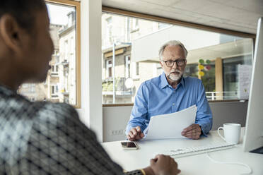 Businessman reading document at desk - UUF23282