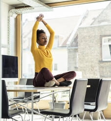 Eine erfolgreiche Geschäftsfrau nimmt sich einen Moment Zeit, um inmitten des Bürochaos innere Ruhe und Ausgeglichenheit zu finden - UUF23347