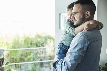 Vater mit Sohn auf dem Balkon stehend und wegschauend - UUF23348