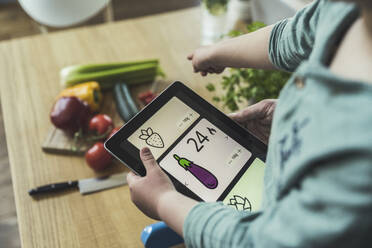 Junge hält digitales Tablet und zeigt auf Gemüse - UUF23372