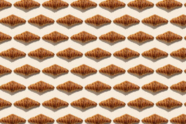 Butter croissants in a row on beige background - GEMF04795