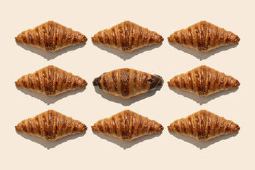 Butter croissants and one chocolate croissant on beige background - GEMF04798