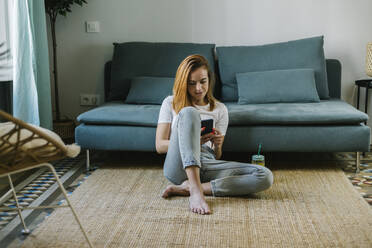 Young woman using mobile phone at home - XLGF01840