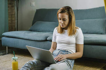 Junge Frau benutzt Laptop zu Hause - XLGF01843