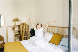 Junge Frau streckt sich auf dem Bett zu Hause - XLGF01887