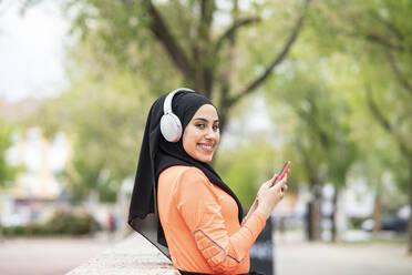 Junge Frau mit Kopfhörern und Smartphone - JCCMF02582