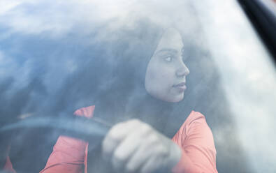 Young woman looking away while sitting in car - JCCMF02593