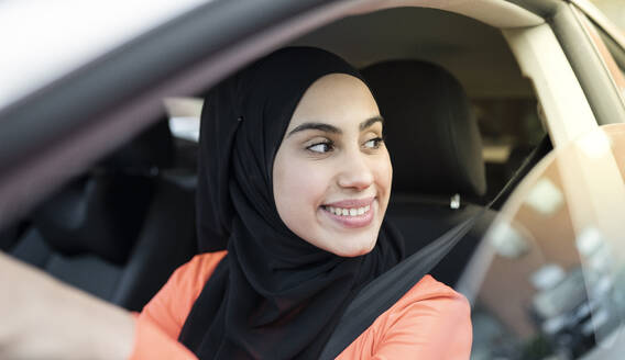 Lächelnde Frau, die aus dem Fenster schaut, während sie im Auto sitzt - JCCMF02594