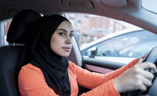 Nachdenkliche arabische Frau schaut beim Autofahren weg - JCCMF02600