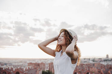 Happy Hispanic woman wearing hat against sky - EBBF03637