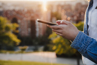 Frau benutzt Smartphone bei Sonnenuntergang - EBBF03644