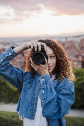 Female photographer taking picture in park during sunset  - EBBF03660