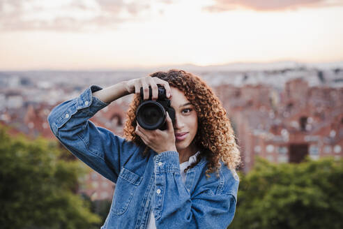 Lächelnde Fotografin beim Fotografieren im Park - EBBF03661