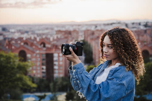 Junge Frau, die durch die Kamera der Stadt fotografiert - EBBF03662