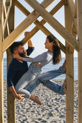 Paar übt Acroyoga an einer Holzstange am Strand - MGRF00230