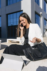 Geschäftsfrau lächelnd im Gespräch auf dem Handy während des sonnigen Tages - JRVF00667