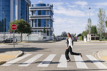 Businesswoman running on road during sunny day - JRVF00692