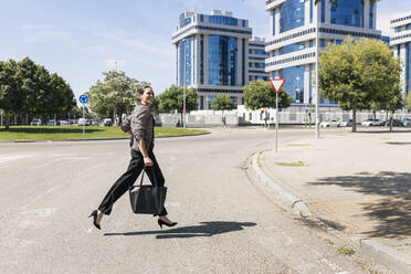 Mature businesswoman running on road in city - JRVF00714