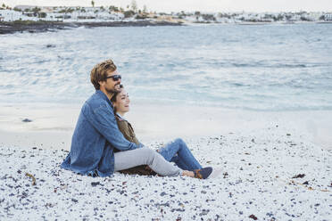 Mid adult couple relaxing together on beach - DGOF02196