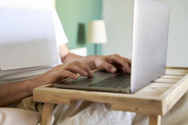 Mann mit Laptop auf Tisch im Schlafzimmer - VEGF04543