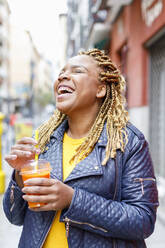 Cheerful woman laughing while holding juice - IFRF00703