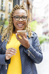 Happy woman with braids talking through speaker on smart phone - IFRF00704