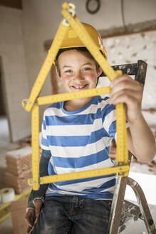 Boy holding house of pocket rule at house during renovation - HMEF01242