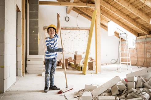 Boy wearing hardhat cleaning house during renovation - HMEF01245