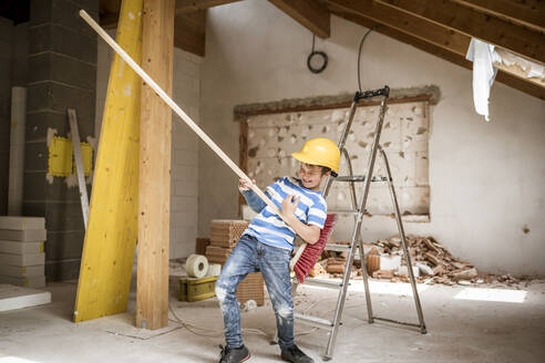Smiling boy playing with broom during house renovation - HMEF01246