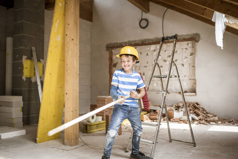 Playful boy holding broom while standing at loft apartment - HMEF01247