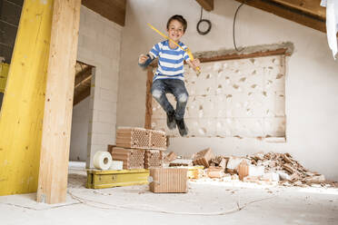 Boy with pocket rule jumping at loft apartment during renovation - HMEF01254