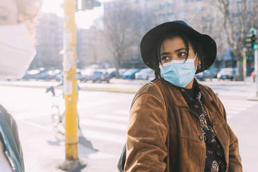 Young woman wearing protective face mask looking at female friend - MEUF02886