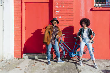 Young friends smiling while leaning on bicycle - MEUF02899