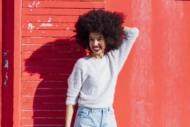 Smiling young woman standing with hand in hair during sunny day - MEUF02909